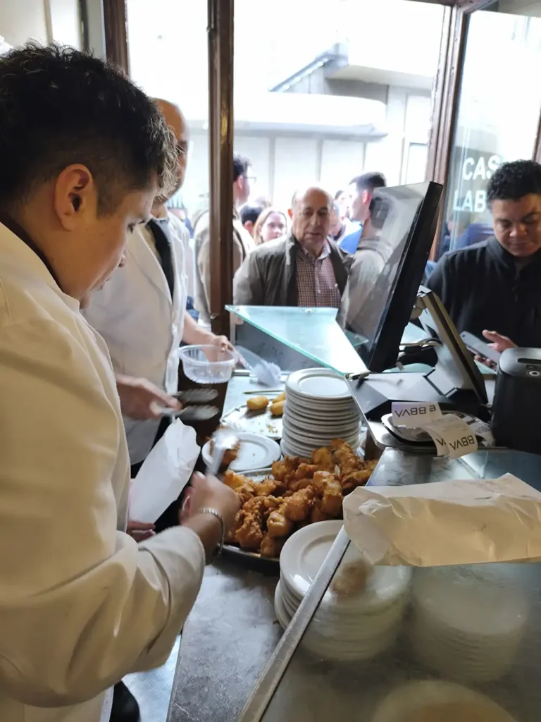 Funcionário da Casa Labra servindo soldaditos de bacalao no balcão da taberna centenária em Madrid