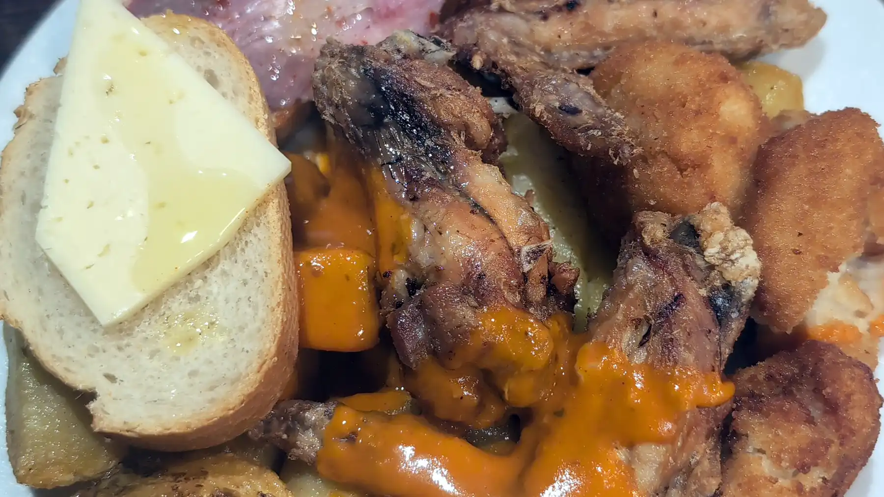 Prato farto de tapas variadas típicas de Madrid com asinhas de frango fritas com molho, croquetes caseiros e fatias de pão com queijo e presunto ibérico.