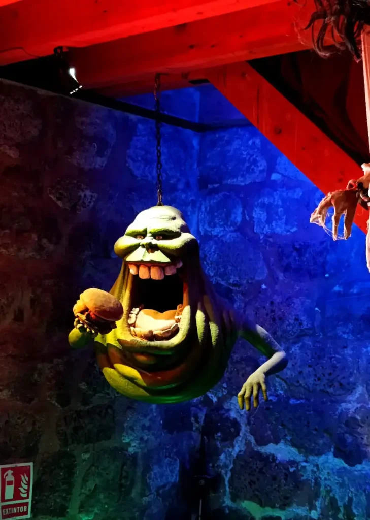 Figura do fantasma Geleia segurando um hambúrguer pendurada por correntes em uma sala com paredes de pedra.