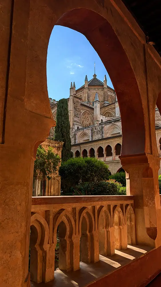 Vista da basílica do Real Mosteiro de Guadalupe enquadrada pelos arcos mudéjares do claustro