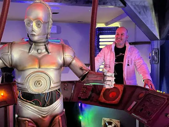 Juan Villa junto a la réplica de C-3PO en la cabina de una nave dentro de la exposición Puerto Espacial.