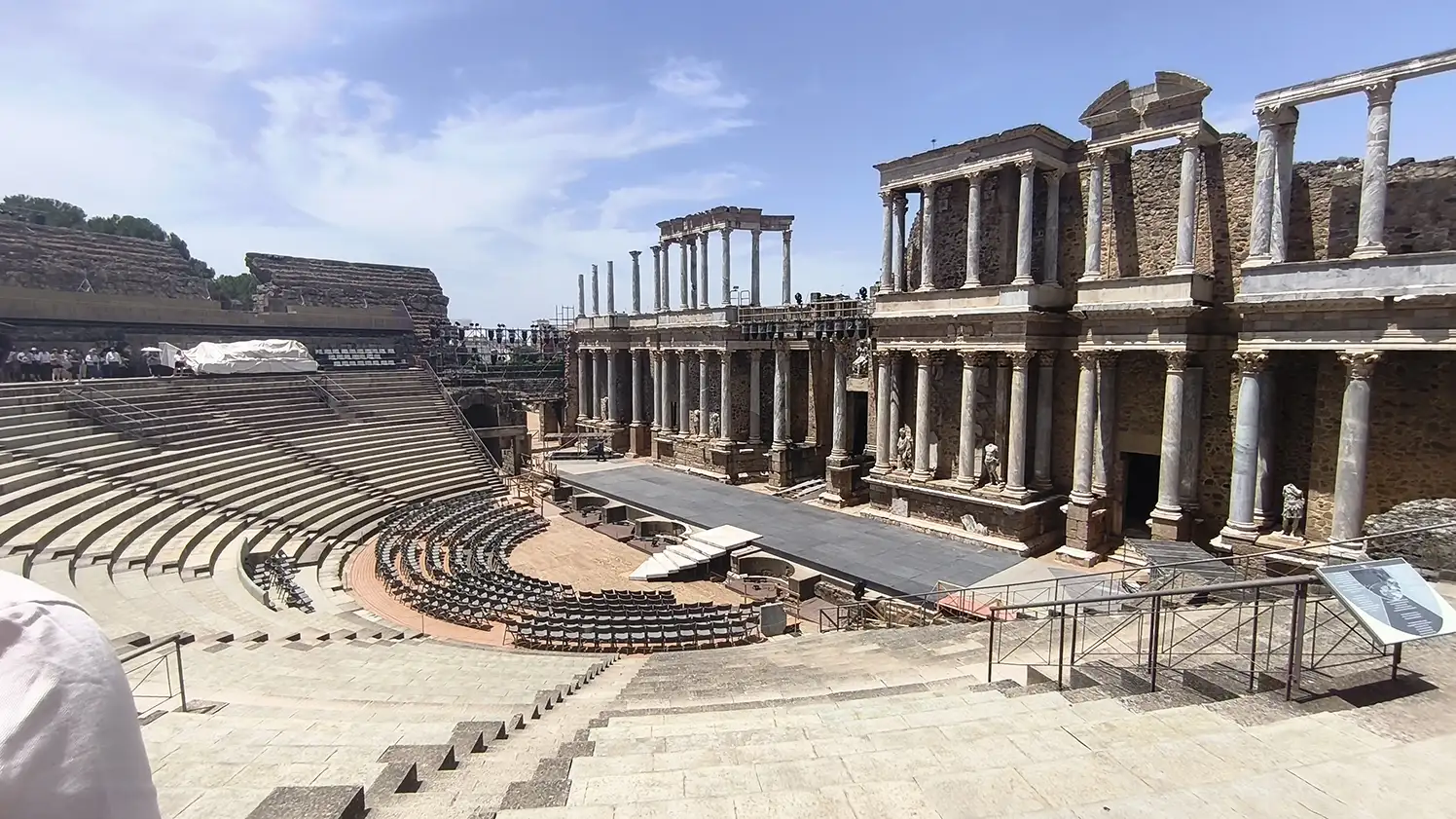 Vista panorâmica do Teatro Romano de Mérida com a scaena ao fundo, colunas de mármore, cadeiras instaladas para espetáculos e arquibancadas em pedra