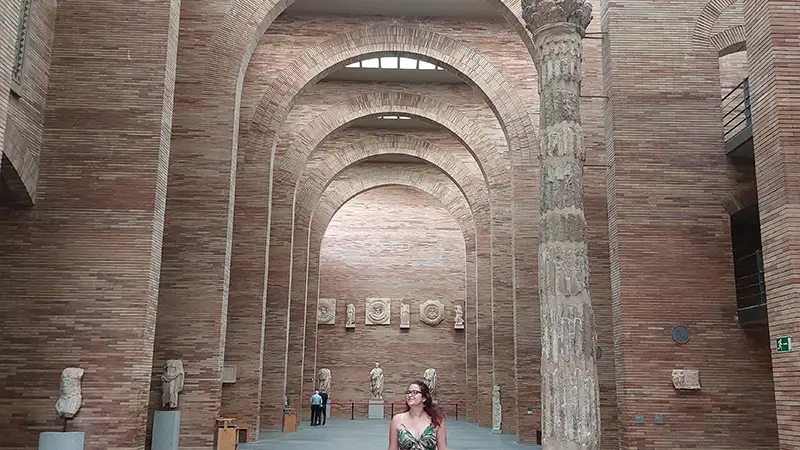 Interior do Museu Nacional de Arte Romana de Mérida com arcos de tijolo, colunas romanas e esculturas expostas na nave central