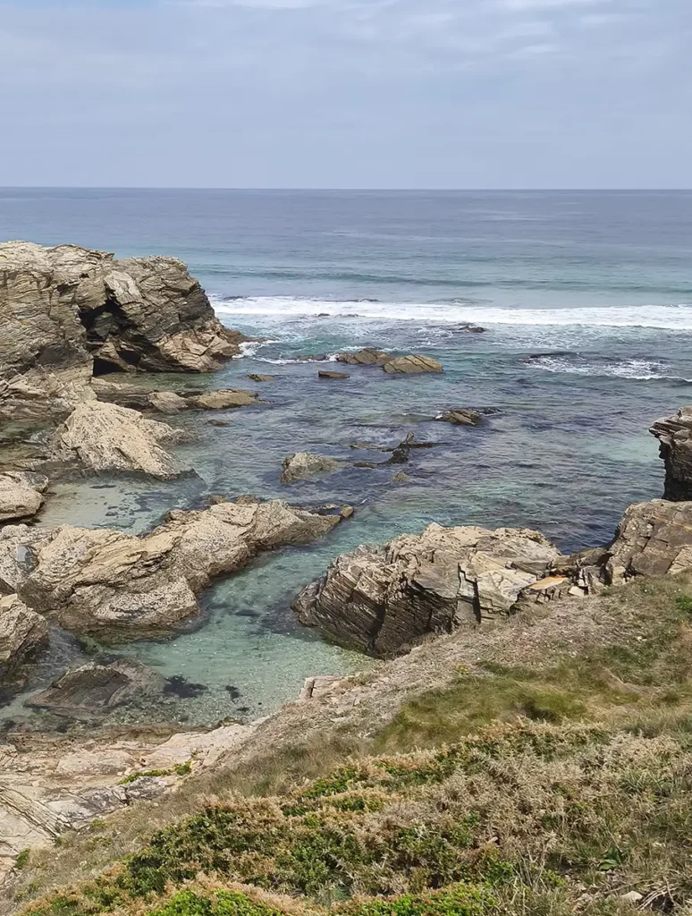 Formações rochosas e piscinas naturais de água turquesa na costa da praia das Catedrais vistas desde o mirador