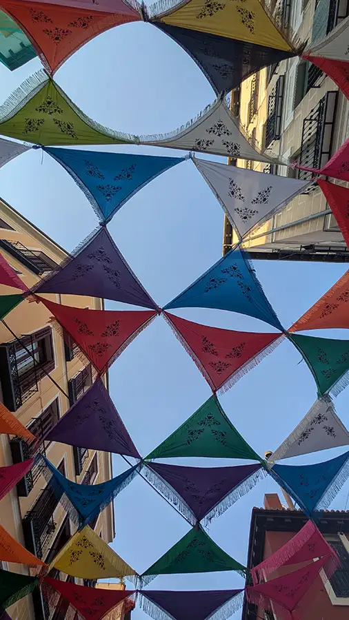 Chales de colores decorando las calles de Madrid durante las Fiestas de Agosto, vistos desde abajo