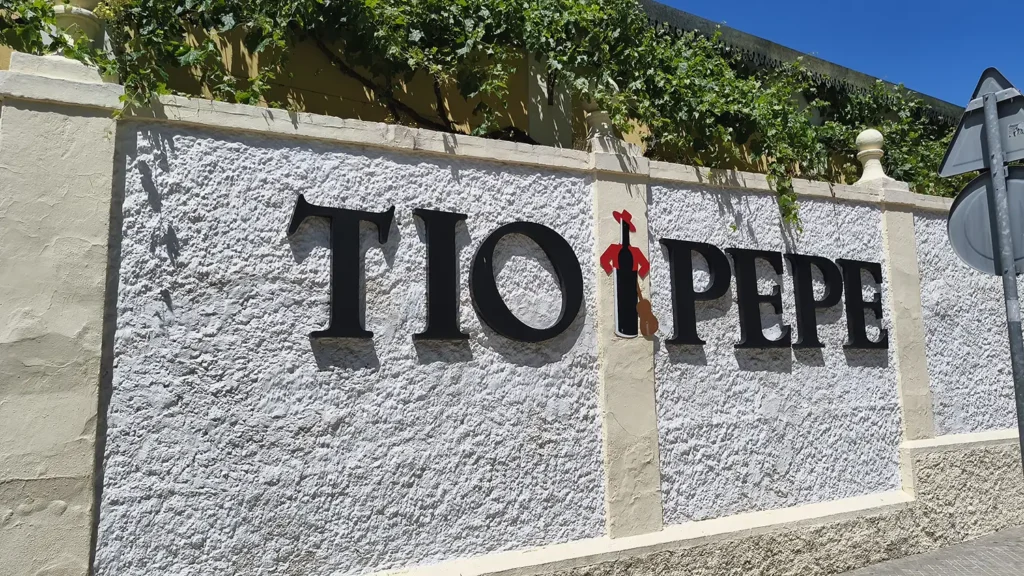 Letreiro Tio Pepe na entrada da vinícola González Byass em Jerez de la Frontera, fachada branca com plantas