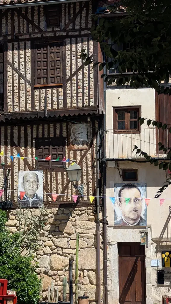 Retratos pintados na fachada de pedra e madeira de uma casa em Mogarraz