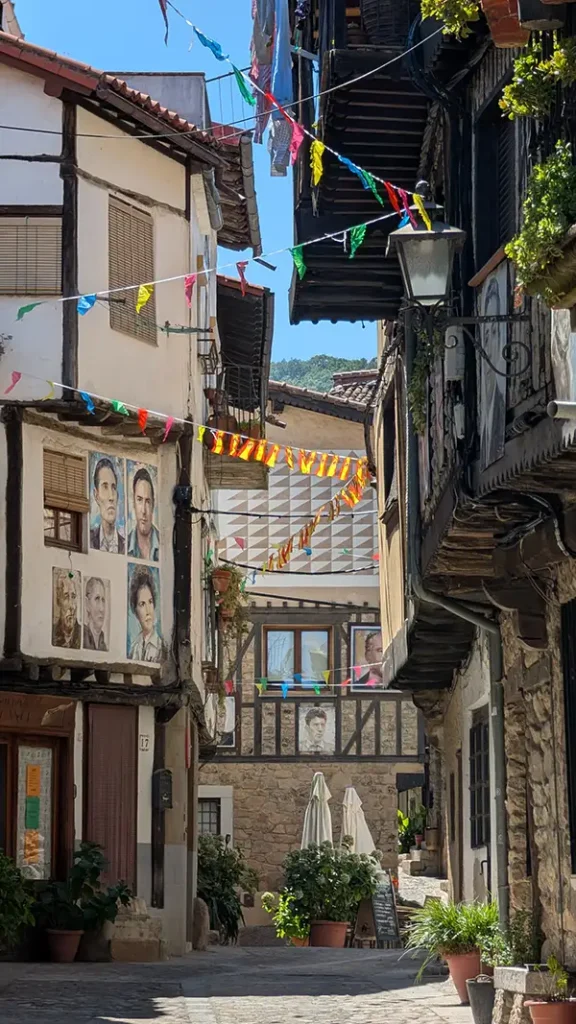 Rua estreita de Mogarraz com retratos agrupados na fachada de uma casa