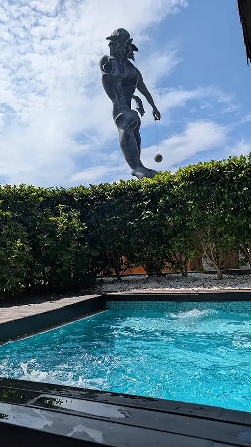 Jacúzi externo do spa do Puebloastur com a escultura Newton de Dalí acima da cerca viva