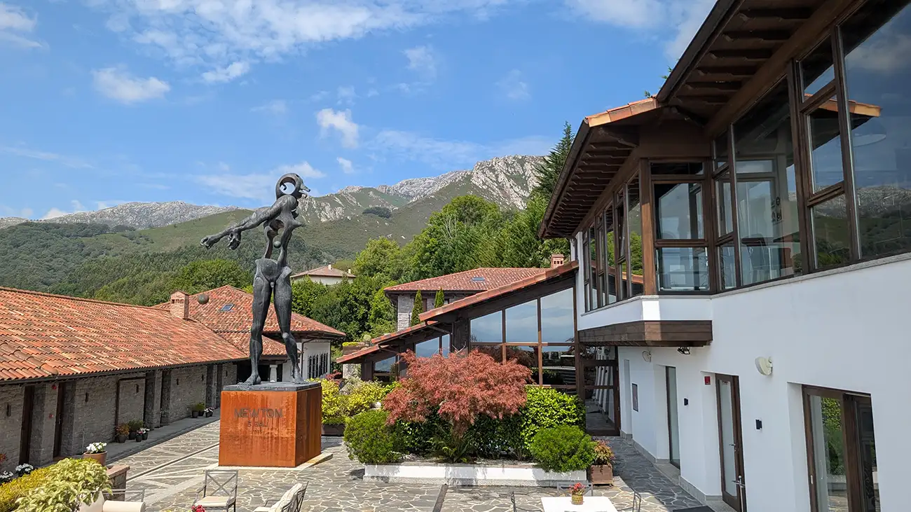 Praça central do Puebloastur com a escultura Newton de Dalí e as montanhas ao fundo