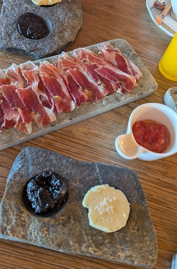 Presunto ibérico, manteiga e compota servidos sobre lousas de pedra no café da manhã do Puebloastur