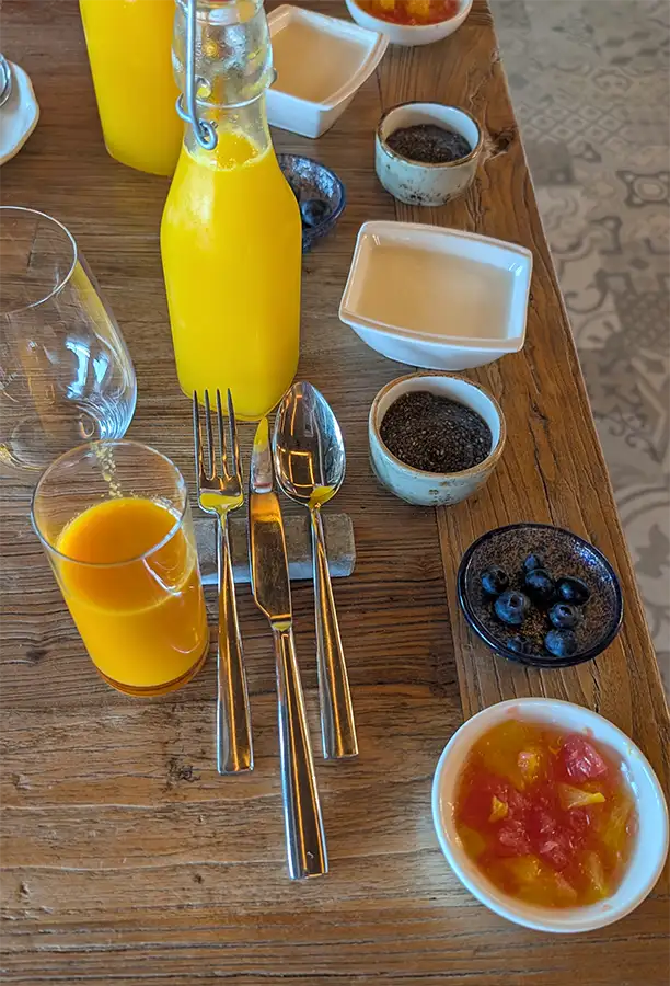Mesa do café da manhã do Puebloastur com suco de laranja natural, iogurte, chia e frutas