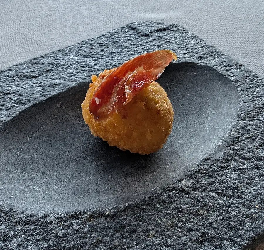 Croquete de presunto ibérico sobre lousa de pedra no menu degustação do Puebloastur
