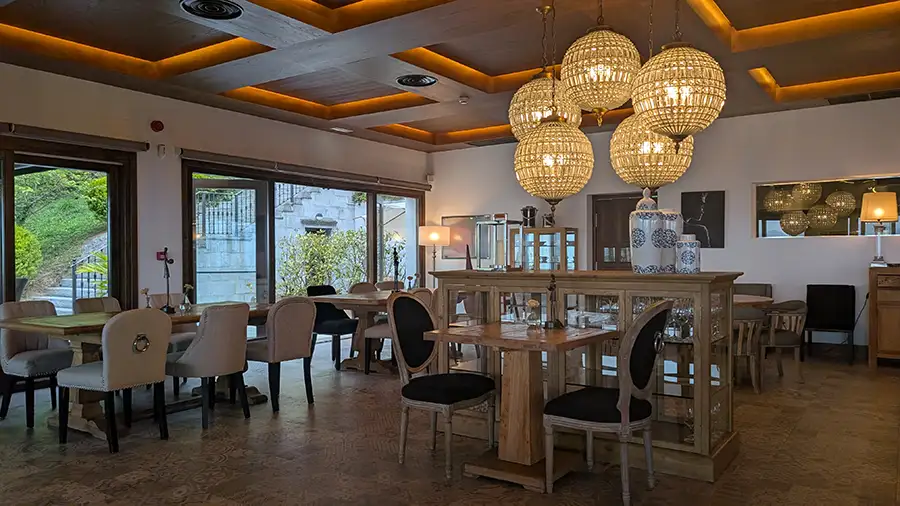 Salão do restaurante do Puebloastur com mesas de madeira e luminárias de cristal