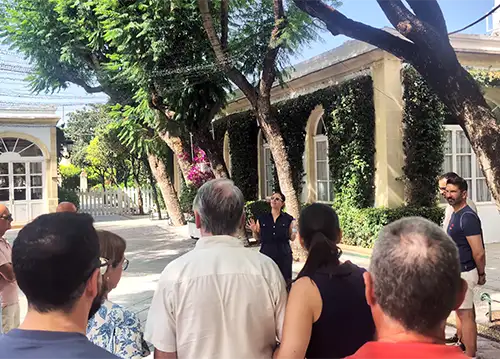 Guia explica detalhes a um grupo de turistas no pátio exterior arborizado da bodega Osborne.