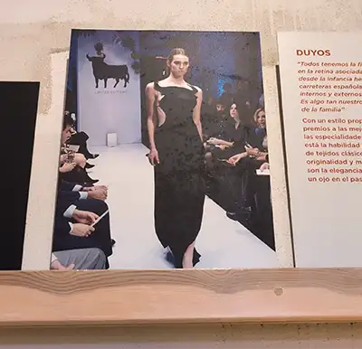 Fotografia de uma modelo num desfile de moda vestindo uma peça preta inspirada na silhueta do touro da Osborne.