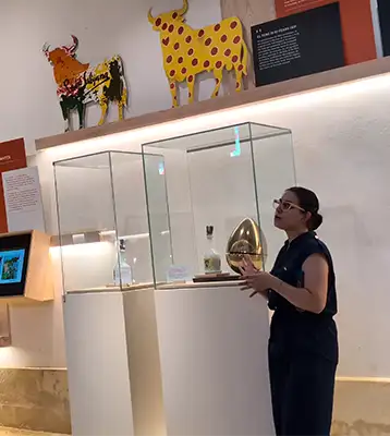 Guia explica a história diante de vitrines com garrafas exclusivas desenhadas por Dalí e touros pintados na parede.