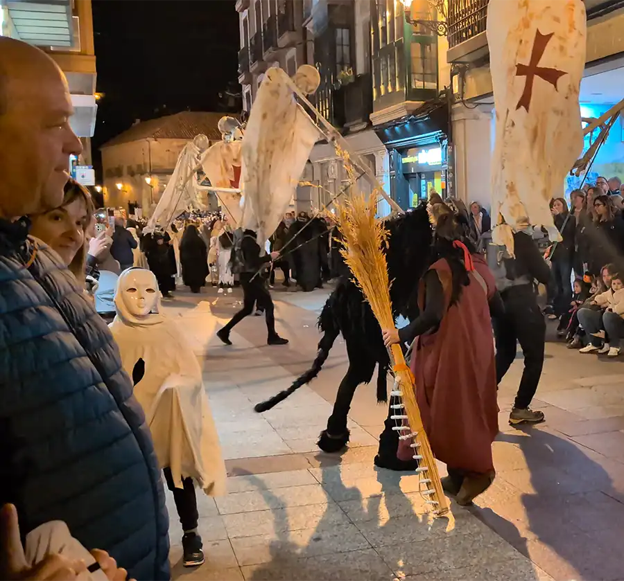 Procissão noturna com figuras de esqueletos e um estandarte com a cruz templária no desfile de las Ánimas.