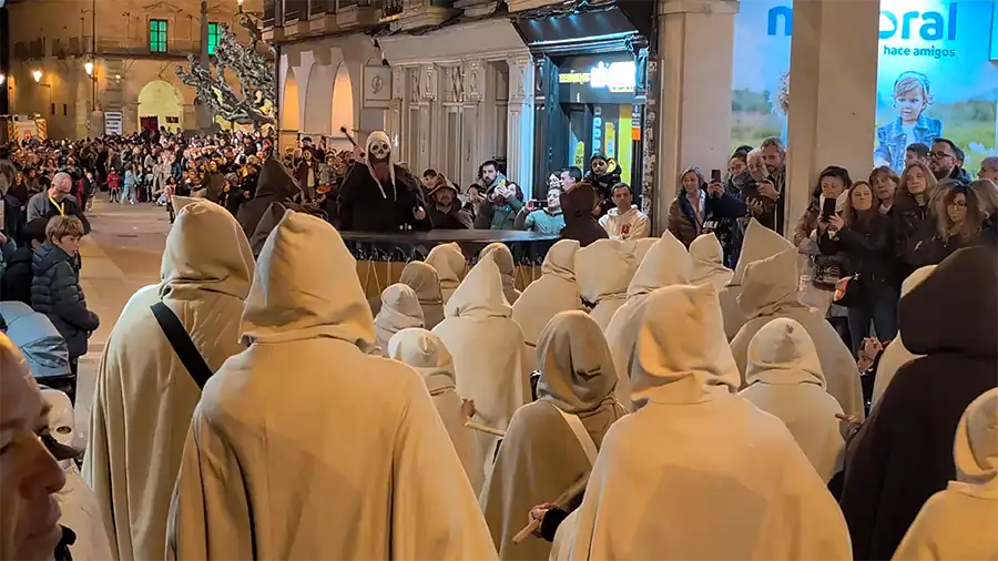Grupo de participantes com capas claras e capuzes caminha pelo centro histórico de Soria durante o festival.