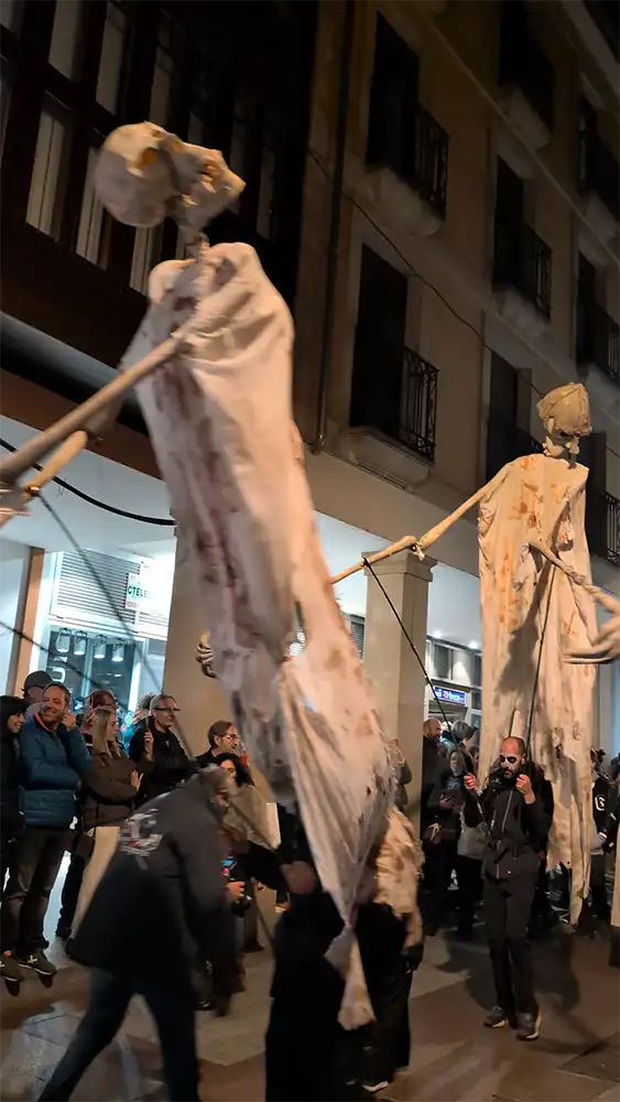 Espectadores observam figuras gigantes de esqueletos transportadas em varas durante o desfile noturno em Soria.