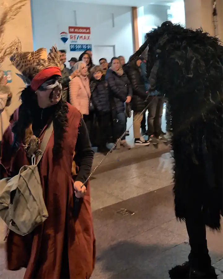 Participante com pintura facial guia criatura com uma corrente no desfile do Festival de las Ánimas em Soria.