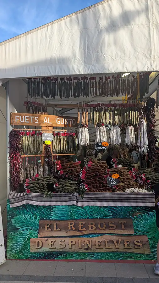 Barraca de fuet com linguiças curadas penduradas e placa "Fuets al gusto" na Fromago, em Zamora