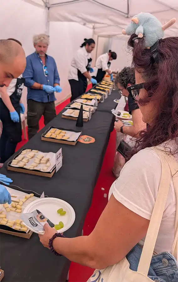 Mesa comprida com bandejas de queijo em cubos e funcionários servindo na galeria do queijo da Fromago, em Zamora